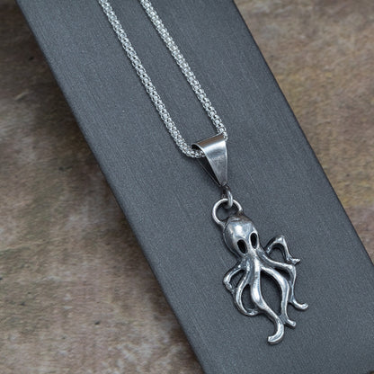 Handcrafted sterling silver octopus pendant with oxidized finish, hanging on a sparkling chain – ocean-inspired artisan necklace by Divella Designs, displayed on gray background.
