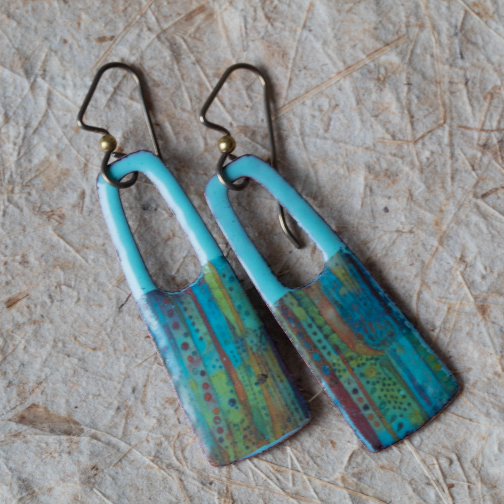Blue rectangular enamel earrings with open cutouts, turquoise tops, striped earthy details, and niobium ear wires.