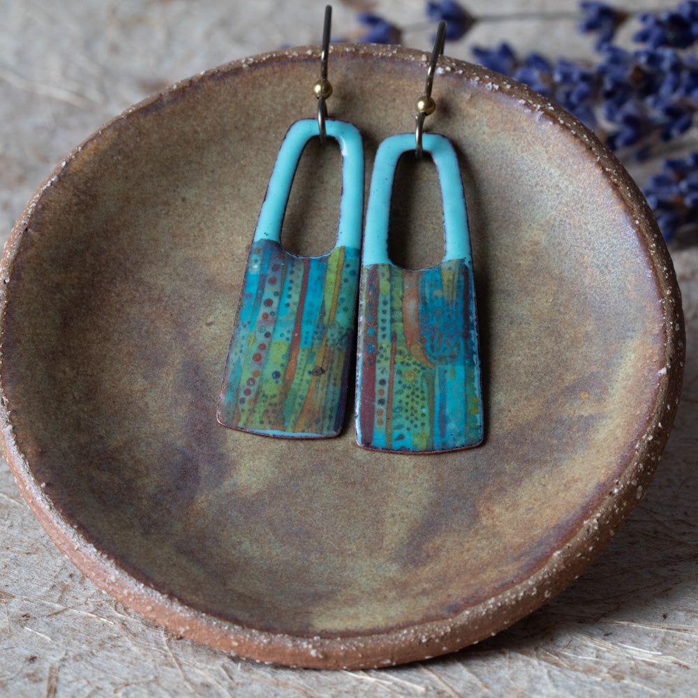 Blue rectangular enamel earrings with open cutouts, turquoise tops, striped earthy details, and niobium ear wires.