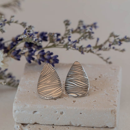 Handmade sterling silver teardrop stud earrings with etched line texture, featuring a minimalist nature-inspired design and oxidized finish