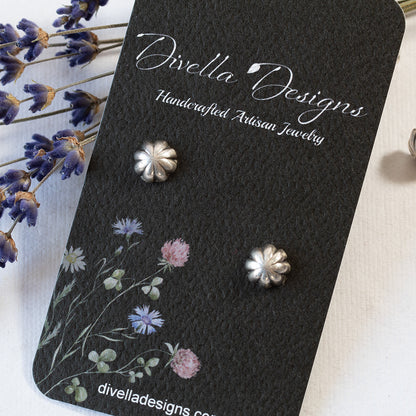Fluted solid silver stud earrings styled with dried lavender sprigs on a  black branded card on a white background.