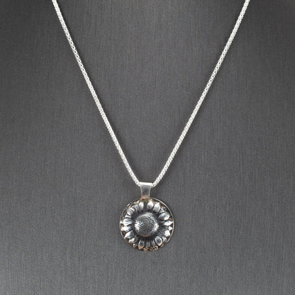 Handcrafted sterling silver sunflower pendant with oxidized details for depth and texture, hanging on a shimmering chain – artisan floral necklace by Divella Designs