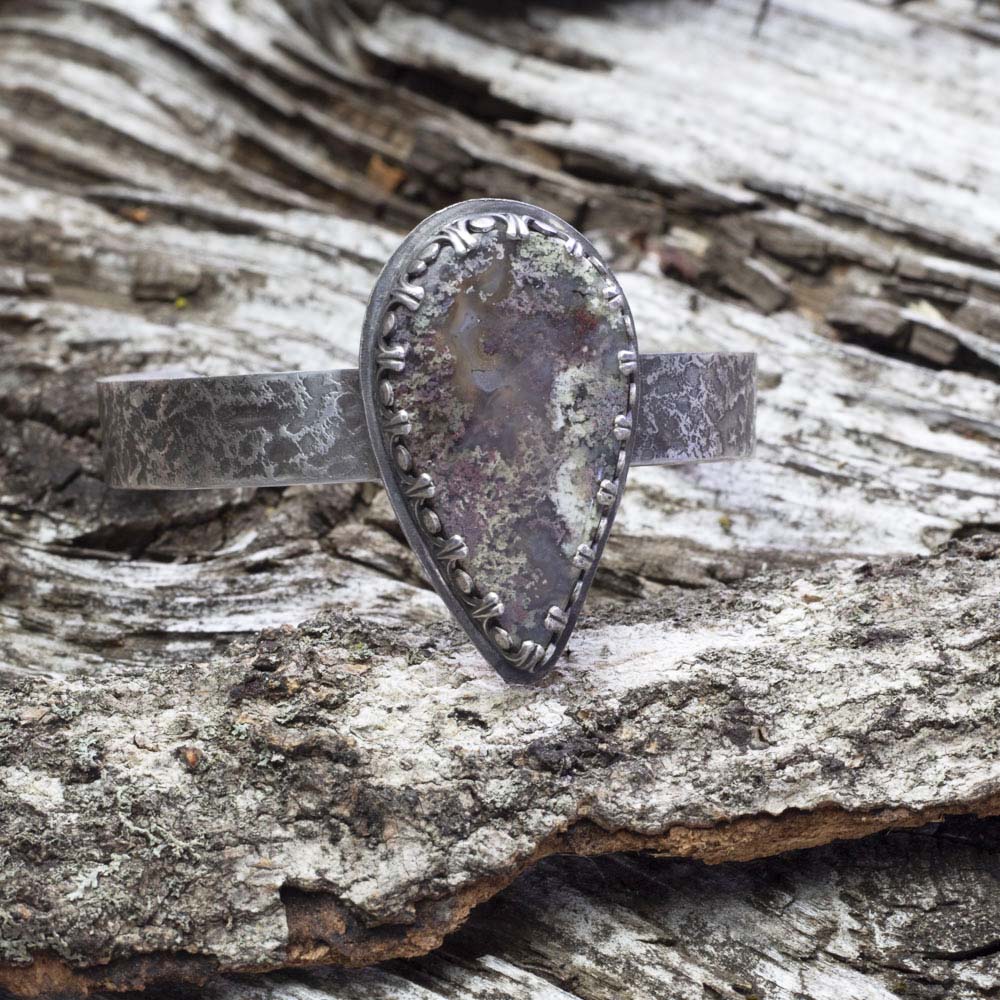 Dendritic moss agate sterling silver cuff bracelet with large teardrop stone, lichen-like pattern, textured silver cuff, and oxidized handmade finish by Divella Designs.