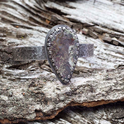 Dendritic moss agate sterling silver cuff bracelet with large teardrop stone, lichen-like pattern, textured silver cuff, and oxidized handmade finish by Divella Designs.
