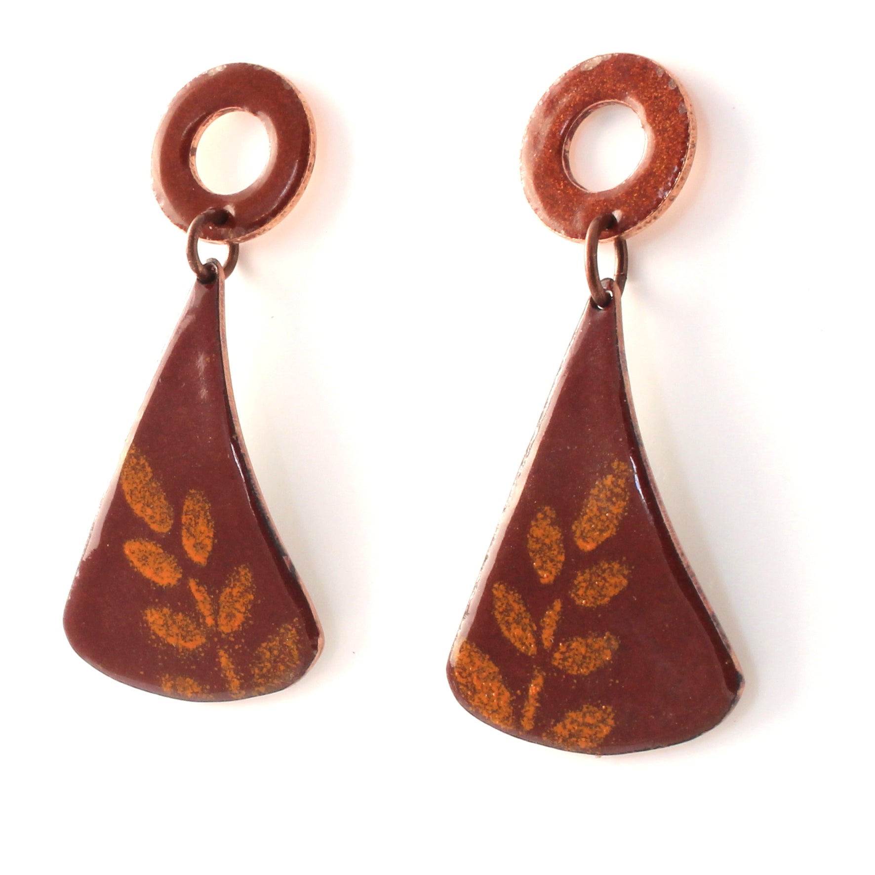 Rusty red enamel dangle earrings with circular copper studs and flared triangular drops, featuring a subtle golden leaf pattern.