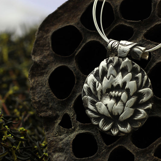 Close up view of the lotus flower pendant on triple-strand sterling AccuFlex wire necklace.