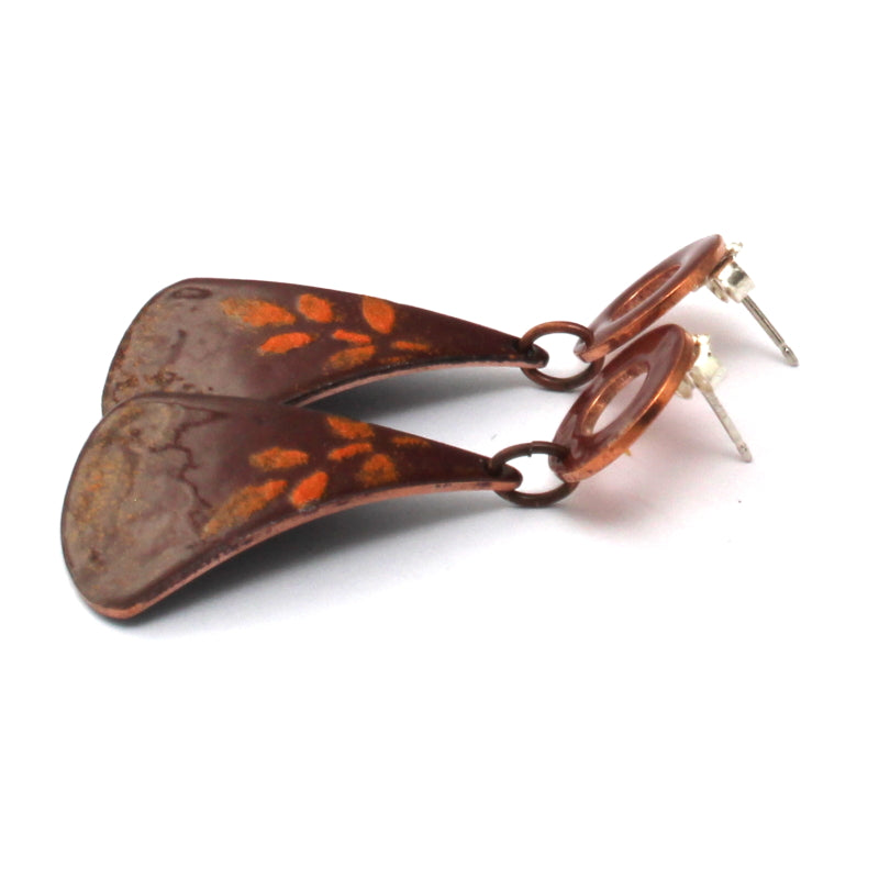 Rust red enamel earrings with orange leaf pattern on white background