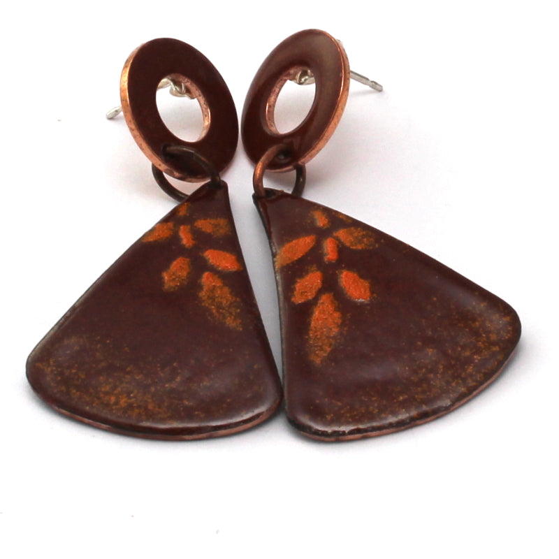Rusty red enamel dangle earrings with circular copper studs and flared triangular drops, featuring a subtle golden leaf pattern.